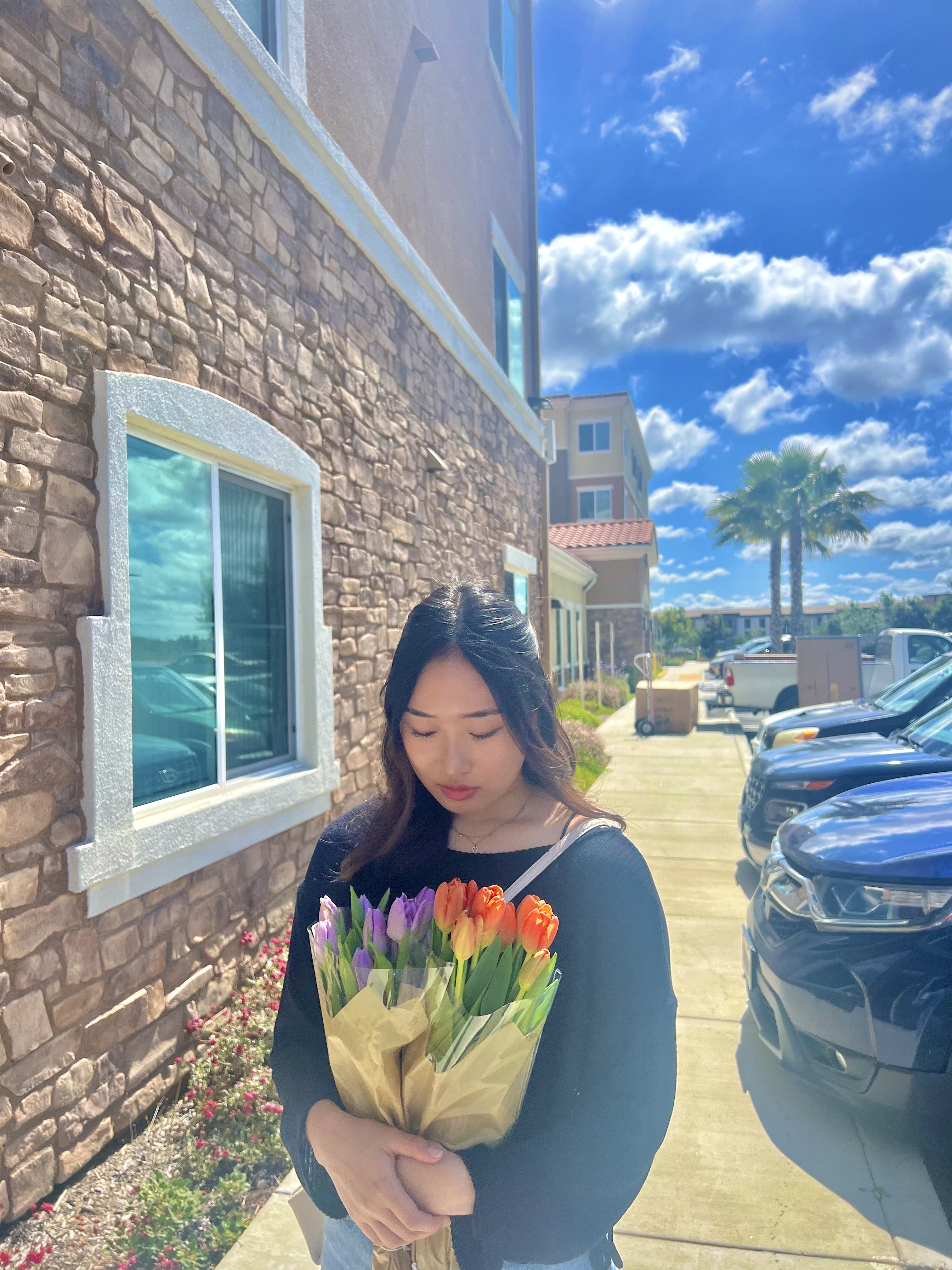 Kate holding a bouquet of tulips next to a brick wall